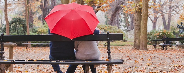older couple sat outside underneath bright umbrella